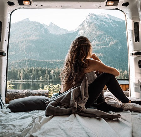Girl sitting in the back on a camper van with a great view