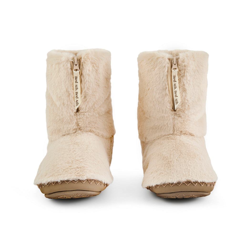 Pair of beige slippers with fur lining on a white background