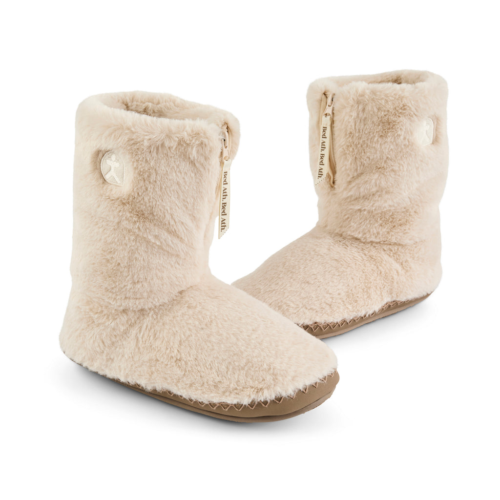 Pair of beige slippers with logo details on a white background