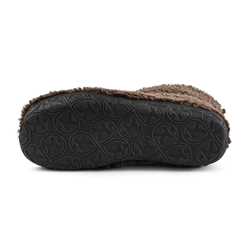 The bottom view of a slip-slipper boot showing a black textured rubber sole with a circular tread pattern and a brown fuzzy shearling-style lining visible along the top edge, set against a plain white background.