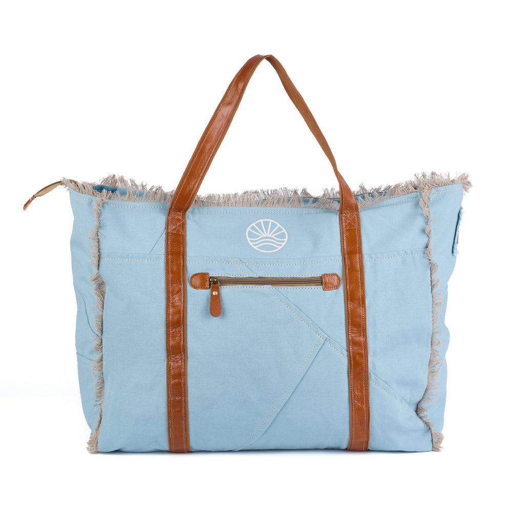 Bonnie: a blue washed canvas beach bag with frayed raw edges, tan leather handles and trim, and an embroidered Beach Athletics logo, back view