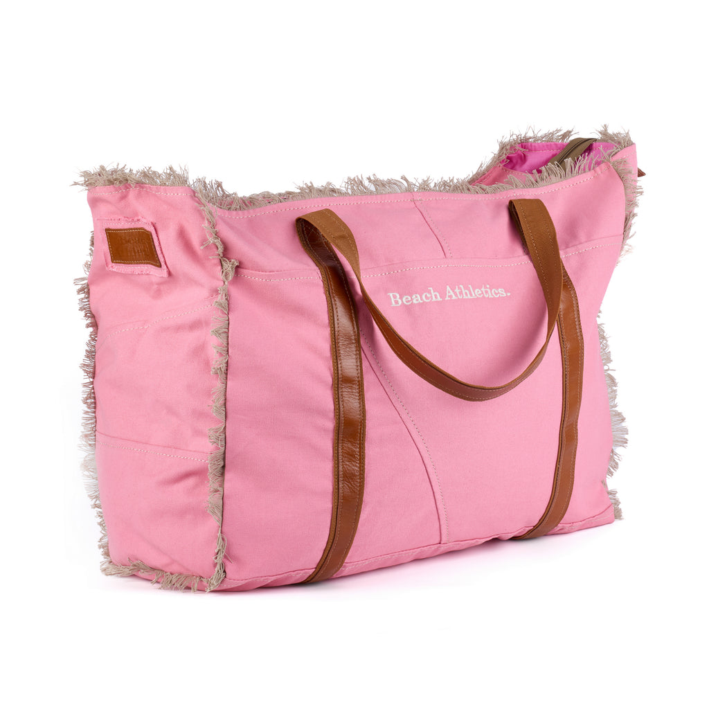 Bonnie: a pink washed canvas beach bag with frayed raw edges, tan leather handles and trim, and an embroidered Beach Athletics logo, shown in full from a second angle