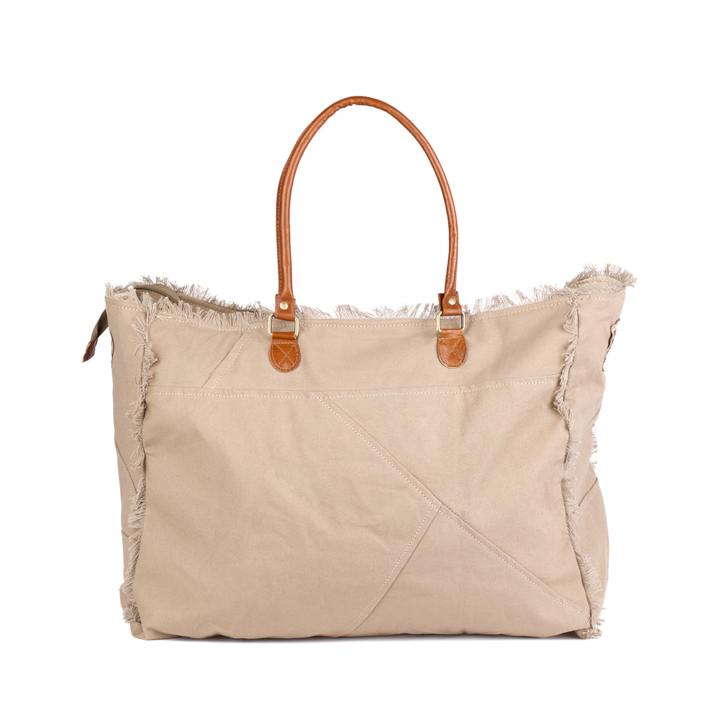 Casey: a beige washed canvas beach bag with frayed raw edges, a tan leather star patch and embroidered Saint-Tropez Canebiers Pampelonne France lettering, back view