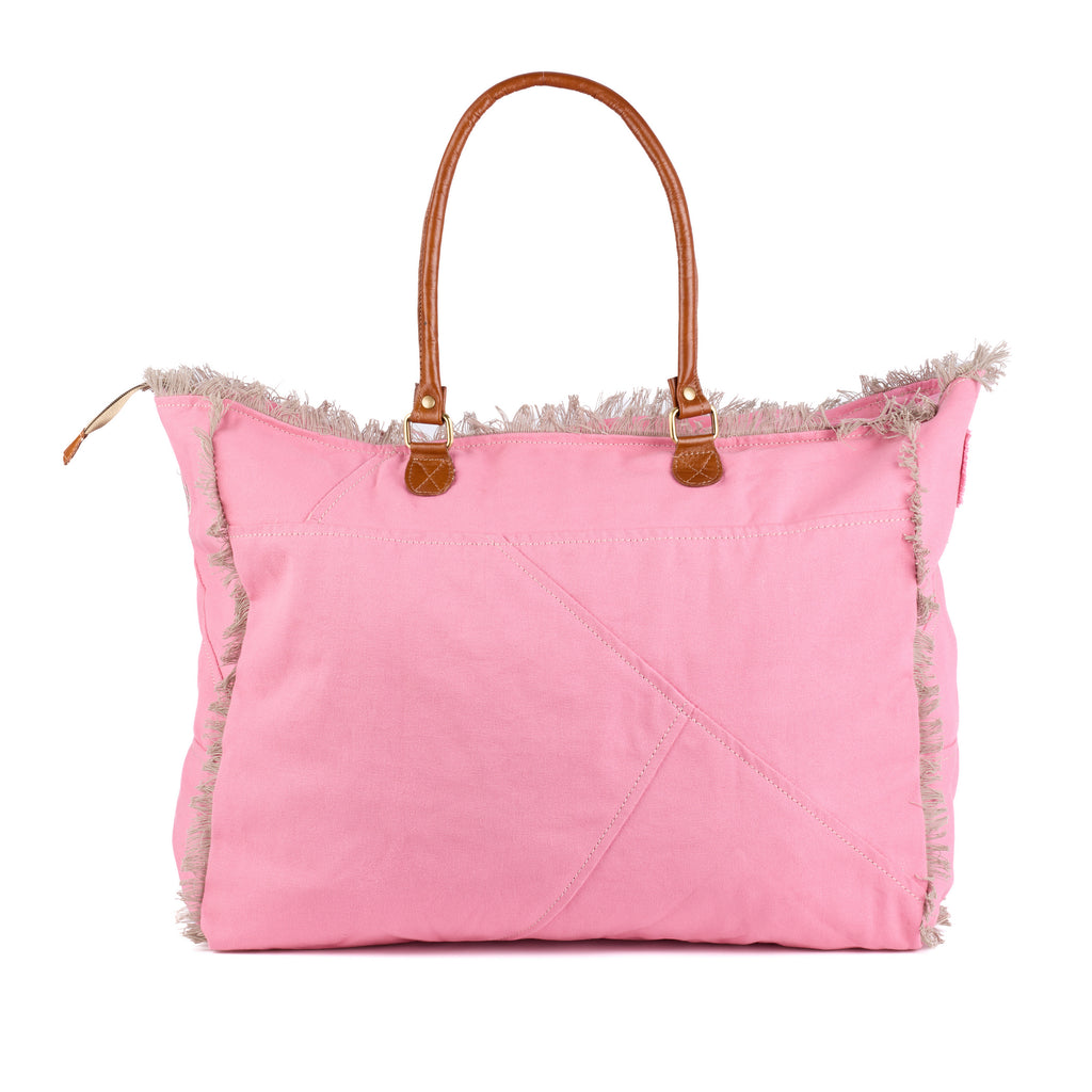 Casey: a pink washed canvas beach bag with frayed raw edges, a tan leather star patch and embroidered Saint-Tropez Canebiers Pampelonne France lettering, back view