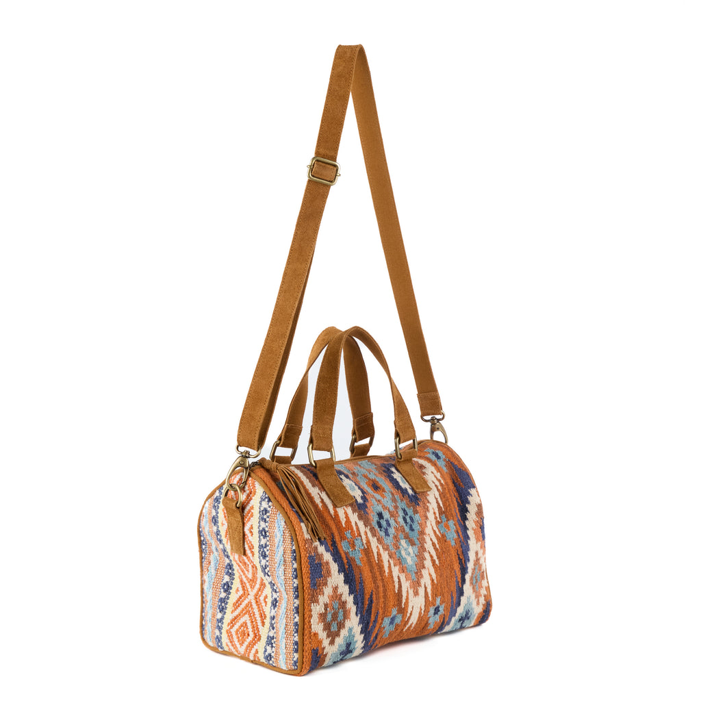 Glastonbury: a boho bowling-style handbag in a blue, orange and cream aztec-pattern weave, with tan suede handles and brass hardware, shown from another angle