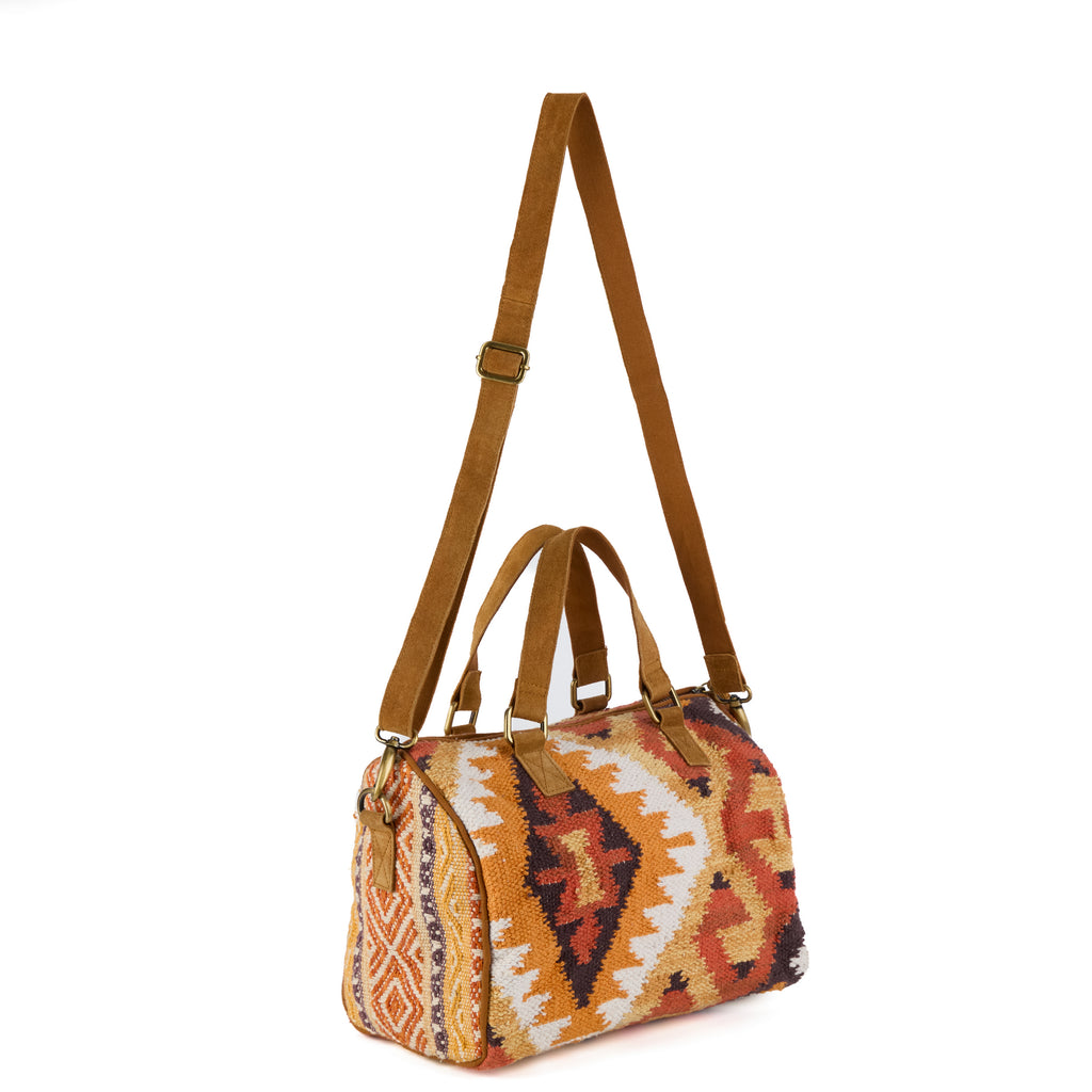 Glastonbury: a boho bowling-style handbag in an orange, rust and cream aztec-pattern weave, with tan suede handles and brass hardware, shown from another angle