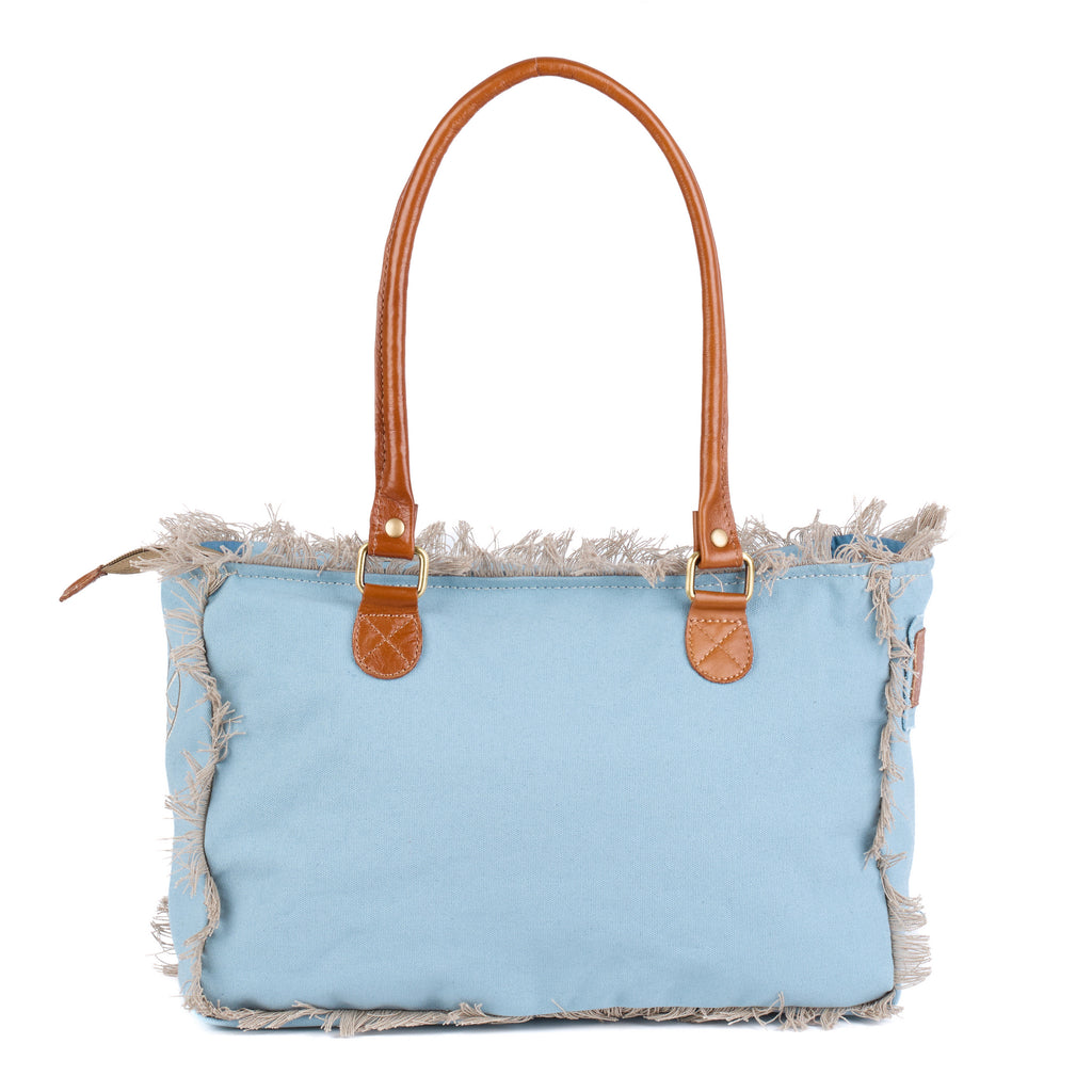 Lani: a blue washed canvas shoulder bag with frayed raw edges, tan leather trim and embroidered Saint-Tropez Pampelonne lettering, back view