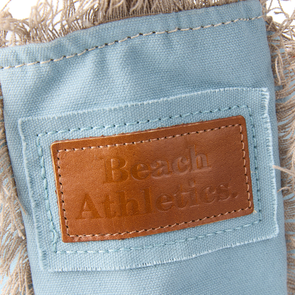 Lani bag (a blue washed canvas shoulder bag), close-up of the embroidered Beach Athletics logo patch