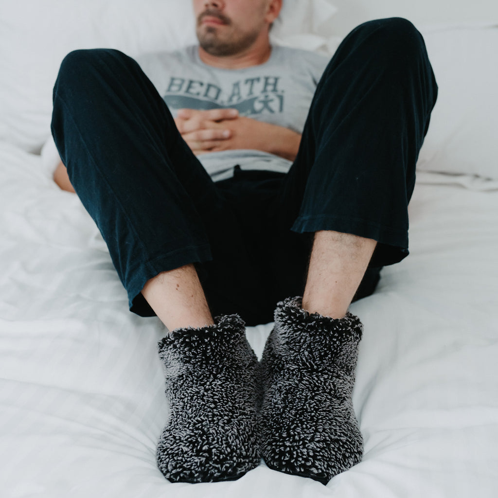 Man laying on a bed wearing Leonardo Black Short Slipper Boots 