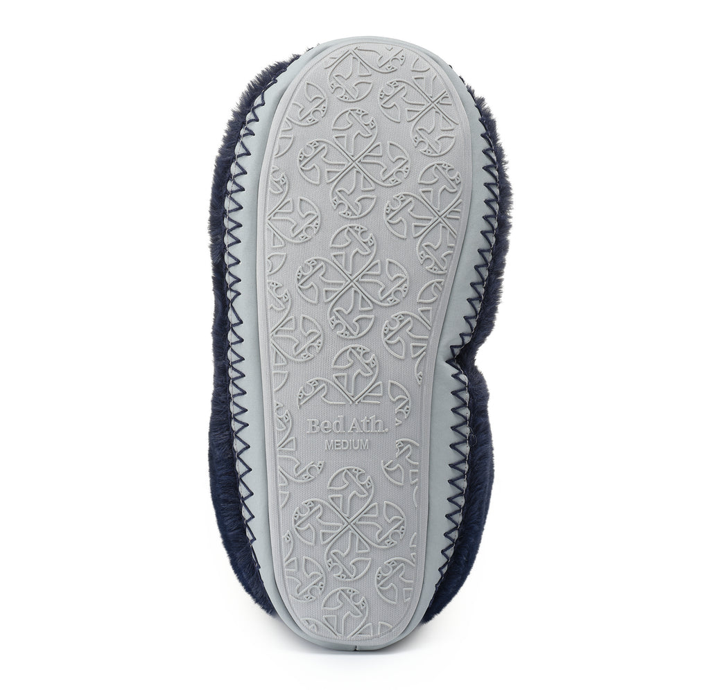 The bottom sole of a medium-sized slippershoe, showing a light gray rubber tread with embossed floral patterns and the brand name 'Bed Att' molded into it. The sides are lined with dark navy blue faux fur, finished with a zigzag stitched edge, on a solid white background.