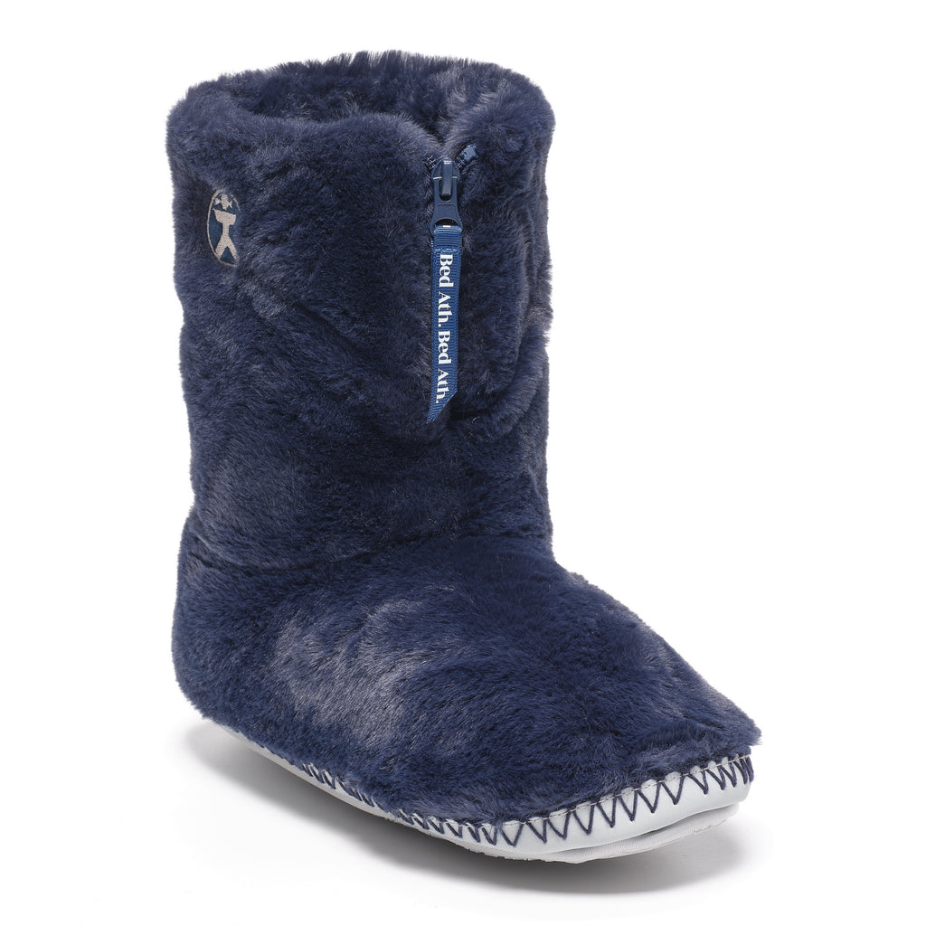 A single navy blue fuzzy slipper boot with a side zipper, shown on a clean white background. The boot features a white zigzag-stitched edge around the sole and a small silver logo on the side.