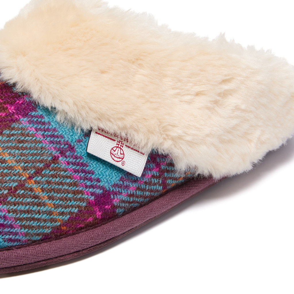 Close-up of a slipper with plaid pattern and fluffy texture, featuring a Harris Tweed brand label.