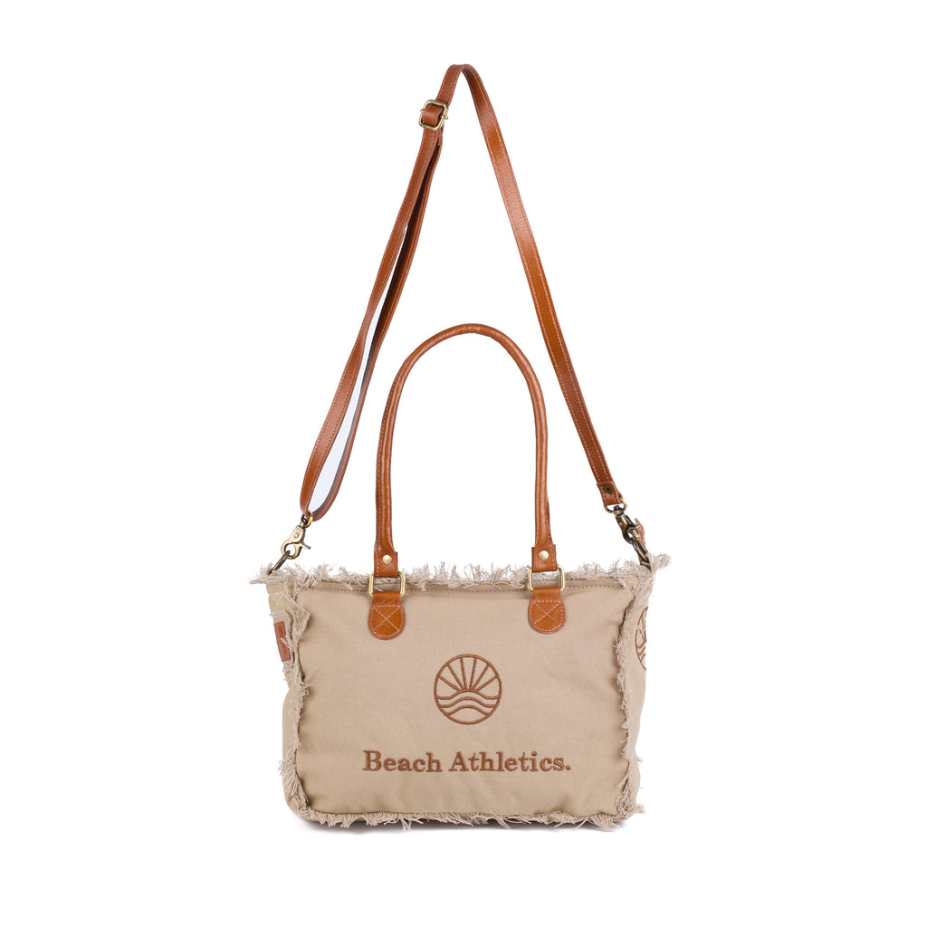 Shauni: a beige washed canvas shoulder bag with frayed raw edges, tan leather trim and an embroidered sunrise Beach Athletics logo, front view, shown in full