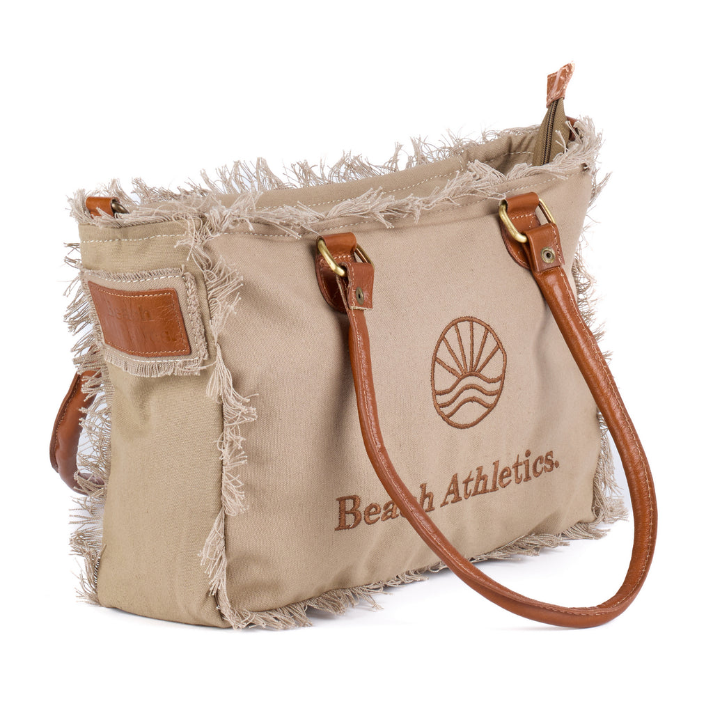 Shauni: a beige washed canvas shoulder bag with frayed raw edges, tan leather trim and an embroidered sunrise Beach Athletics logo, shown at an angle