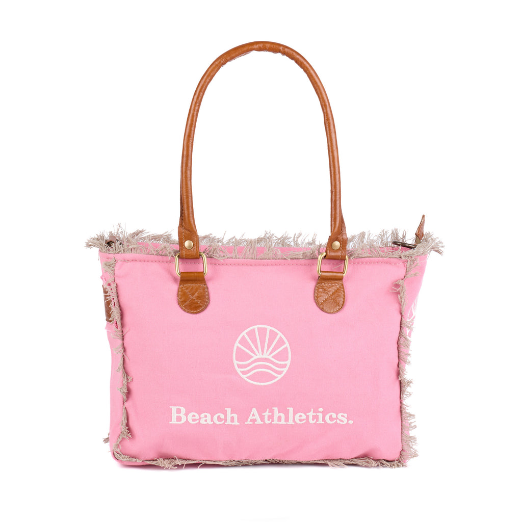 Shauni: a pink washed canvas shoulder bag with frayed raw edges, tan leather trim and an embroidered sunrise Beach Athletics logo, front view with the handles raised