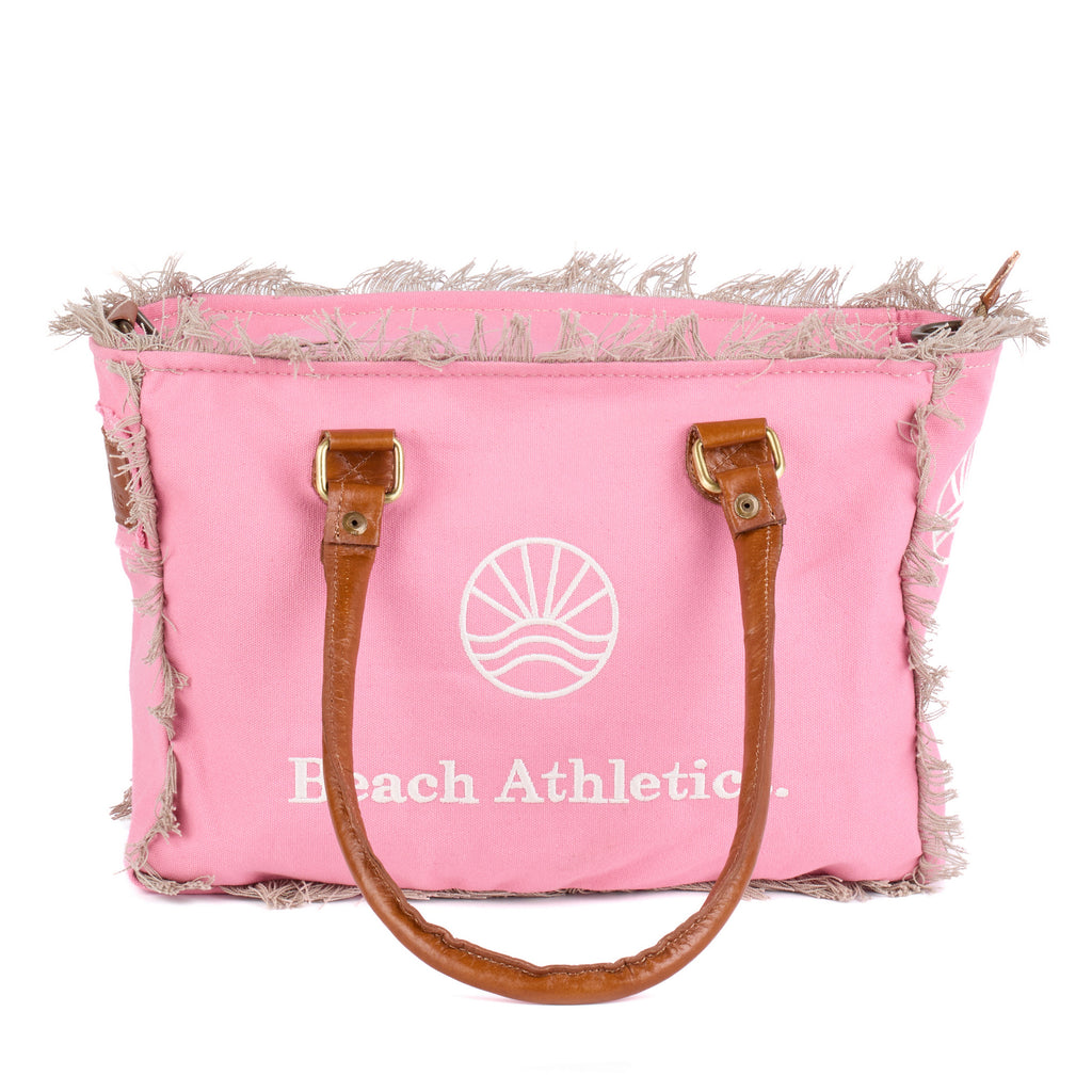 Shauni: a pink washed canvas shoulder bag with frayed raw edges, tan leather trim and an embroidered sunrise Beach Athletics logo, front view